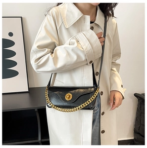 Detail view of a vintage black square bag with a chunky gold chain and metallic buckle