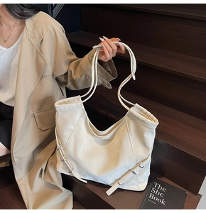 Gros plan détaillé du sac cabas en cuir crème avec des boucles métalliques réglables