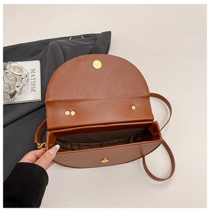 Detail view of the brown semi-circle bag interior with striped lining and gold magnetic closure