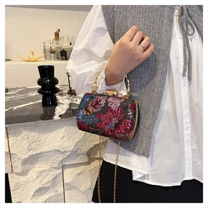 Close-up of floral sequin embroidery and gold bamboo handle on luxury shell bag
