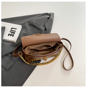 Detail view of brown leather bag interior with striped lining and gold chain strap