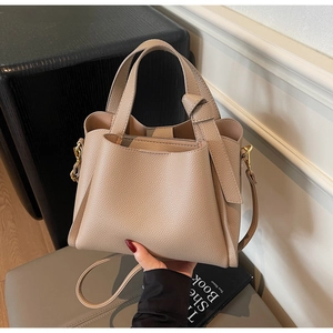 Dettaglio della borsa beige in pelle martellata con manico a nodo e dettagli in oro