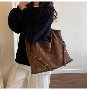 Détail d'un grand sac cabas marron en similicuir avec boucle en métal porté par un mannequin