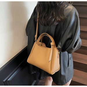 Dettaglio borsa marrone in pelle litchi con finiture dorate e design plissettato