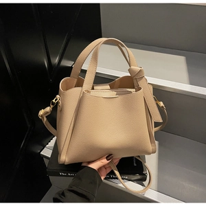 Dettaglio macro della borsa beige in pelle martellata con nodo laterale e cuciture