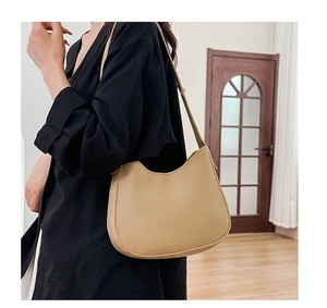 Side view of beige saddle bag with smooth matte finish and refined stitching details