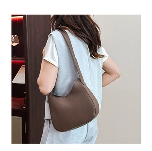 Brown matte leather hobo bag shown on model in a minimalist indoor setting