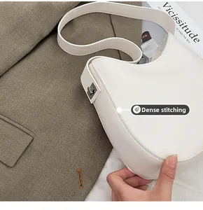 Detailed view of precise stitching and silver metal buckle on a white leather shoulder bag
