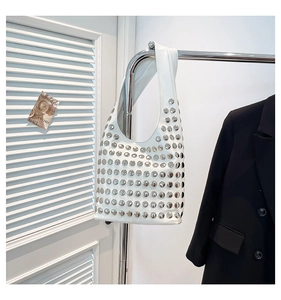 Gros plan d'un sac hobo en cuir blanc avec des clous métalliques argentés décoratifs