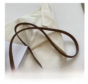 Close-up of brown leather shoulder strap with gold metal hooks on tweed texture