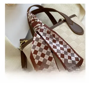 Detail of beige lychee leather handbag with a brown silk scarf wrapped around the handle