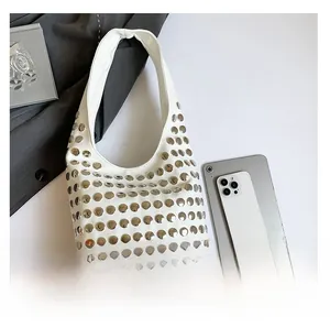 Détail du grand sac hobo en cuir blanc avec rivets et comparaison de sa capacité de stockage