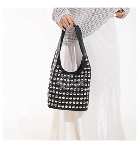 Détail d'un sac sous le bras en cuir noir avec rivets argentés et poignée supérieure