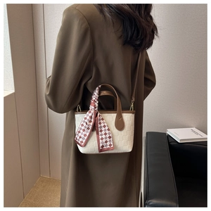 Close-up of a cream checkered handbag with brown trim and silk scarf detail