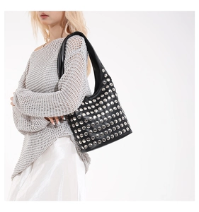 Vue latérale du sac porté épaule noir à rivets sur mannequin dans un studio blanc