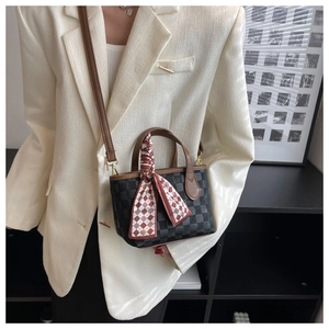 Detail of vintage checkered crossbody bag with brown handle and decorative silk scarf