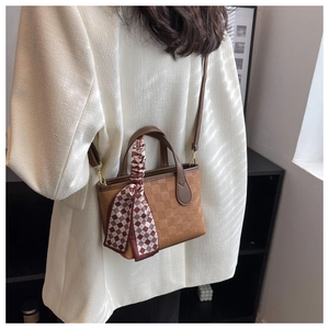 Brown textured leather crossbody bag with silk scarf handle on model in white suit