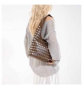 Sac à bandoulière vintage en cuir marron avec rivets argentés porté par un mannequin
