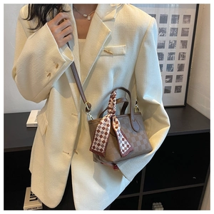 Close-up of brown checkered handbag with silk scarf detail on a minimalist model outfit
