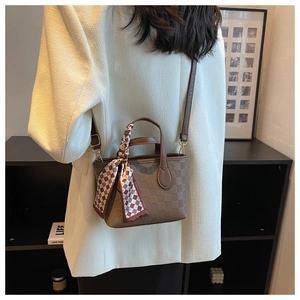 Close-up of brown checkered handbag with decorative silk scarf and gold hardware accents