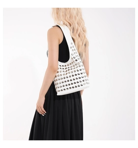 Vue détaillée d'un sac demi-lune blanc clouté d'argent porté sur une robe noire