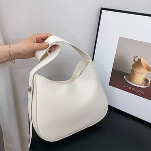 Minimalist white PU leather hobo shoulder bag with a wide strap held by hand