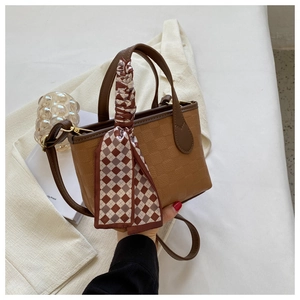 Close-up of brown textured small tote with plaid silk scarf detail and crossbody strap