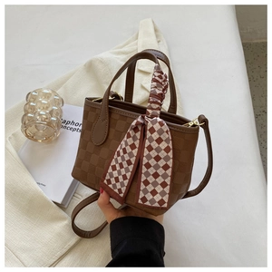 Detail of checkered leather tote bag with a decorative silk scarf and metallic handle hardware