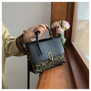 Detail of leopard print crossbody bag on a wooden windowsill with pink roses