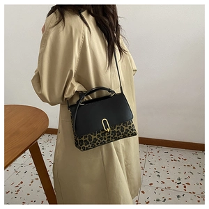 Detail of a leopard print leather handbag featuring a golden U-shaped buckle and strap