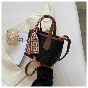 Detail of vintage plaid handbag with brown leather trim and silk scarf accessory