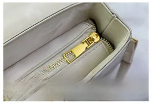 Détail de la fermeture éclair dorée sur sac en cuir crème avec des coutures de précision