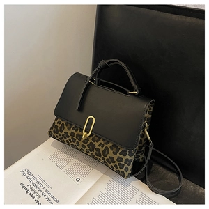 Detail of leopard print crossbody bag with gold lock hardware on magazine background