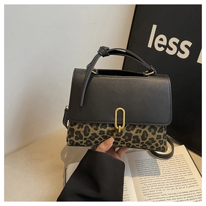 Detail of leopard print handbag with golden oval metal clasp and black leather trim