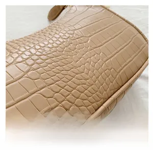 Detailed close-up of khaki crocodile pattern texture and stitching on the leather handbag