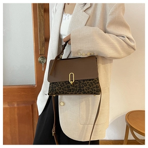 Detailed view of leopard print crossbody bag with golden oval lock on a female model