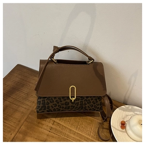 Detail of leopard print crossbody bag featuring a golden oval metal buckle and leather strap