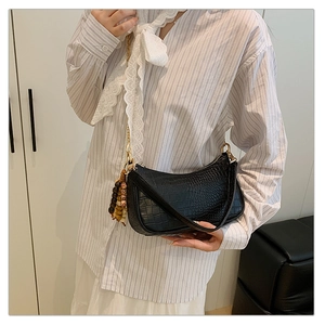 Close-up of black crocodile pattern baguette bag with decorative beaded chain strap
