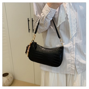Close-up of black crocodile pattern baguette bag with vintage wooden bead charm