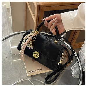 Détail du sac à main en velours noir avec fermoir doré et pendentif à pompon tissé