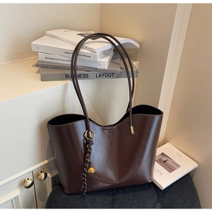 Detail of dark brown leather tote bag with decorative tassel and metal ball charm