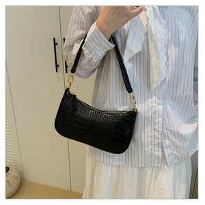 Close-up of black crocodile pattern underarm bag with gold metal buckle on a model
