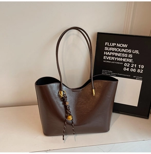Close-up of dark brown PU leather tote bag with gold metal hardware and decorative bell
