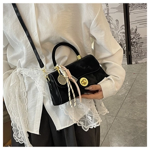 Détail d'un sac à main vintage noir avec fermoir doré, breloque raquette et foulard en soie