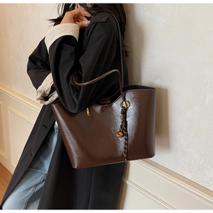 Detail of dark brown faux leather tote bag with drawstring tassel and slim shoulder strap