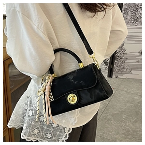 Détail du sac bandoulière noir avec fermoir rotatif doré et poignée décorée de soie