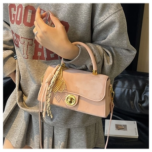 Détail d'un sac à main en cuir verni rose avec fermoir doré et breloque tressée