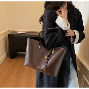 Brown tote bag detail with golden hardware and black and white woven rope handle