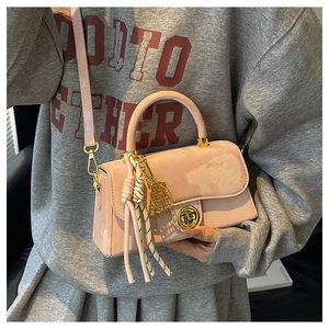 Détail du sac à main rose brillant avec fermoir doré et pendentif de raquette de tennis