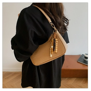 Detail of crocodile embossed faux leather underarm bag with wooden bead fringe tassel
